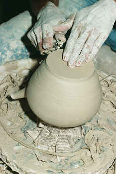 Someone forming a clay pot on a spinning wheel.