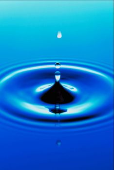 A picture of a drop going into some water and from that entry, another drop is made that flies up a ways.